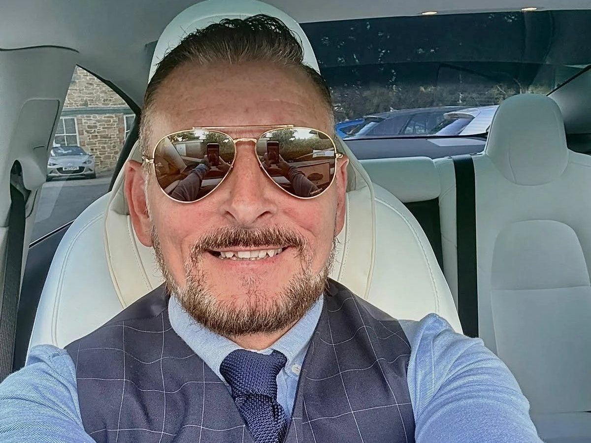 Wayne, dressed for chauffeur work, at the wheel of the ZensCars Tesla